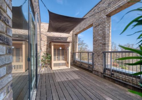 una porta a vetri aperta su un edificio in mattoni con terrazza di Cambridge - hot tub, sauna, parking, pool table a Trumpington