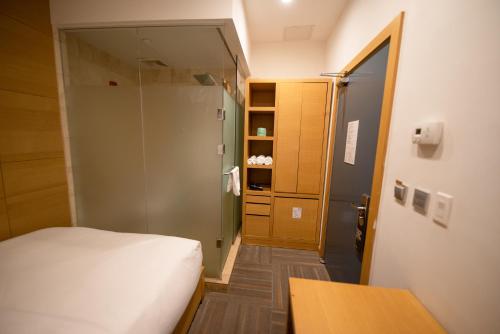 a small bedroom with a bed and a glass door at The One Boutique Hotel in Queens