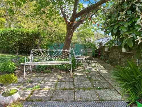 a bench sitting in a garden under a tree at Beautiful renovated stone house for Dog friendly, Quayside location in Newport