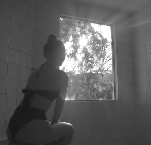 a woman sitting in a bathroom looking out a window at Pousada Alfa e Ômega in Alto Paraíso de Goiás