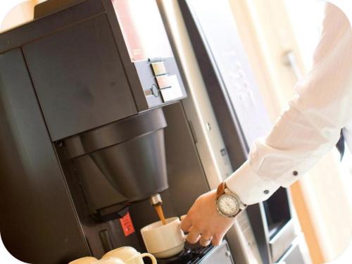 a person in a white shirt is putting a cup in an oven at Hotel Brisbanes - Vacation STAY 65799v in Miyazaki