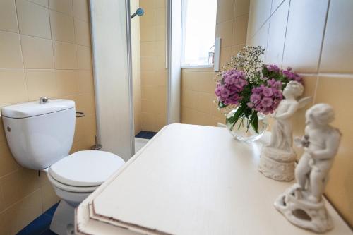 a bathroom with a toilet and a vase of flowers on a counter at Villa Giannina B&B in Taormina