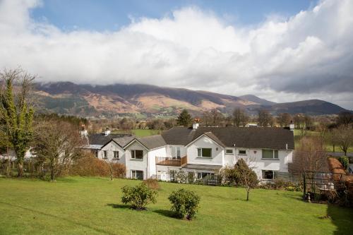 a house in a field with mountains in the background at Hermiston Guest House in Keswick