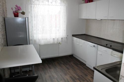a kitchen with white cabinets and a refrigerator at BS Business Travelling Hannover City in Hannover