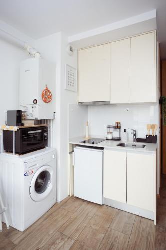 une cuisine avec des armoires blanches et une machine à laver dans l'établissement Studio cosy 28 mn aéroport CDG 34 mn chatelet, à Livry-Gargan