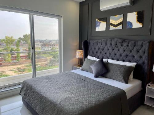 a bedroom with a large bed with a large window at Starlit By Zameen Opal in Lahore