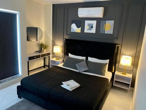 a bedroom with a large black bed with two lamps at Starlit By Zameen Opal in Lahore