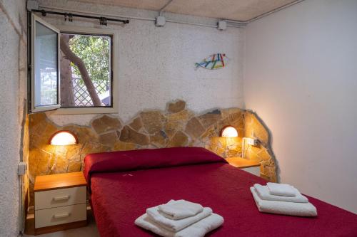 Un dormitorio con una cama roja con dos toallas encima. en Appartamento Depandance 1 Villa Ada Punta Prosciutto, en Punta Prosciutto