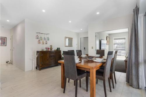 a dining room with a wooden table and chairs at Sun and Surf Retreat - Papamoa Beach Holiday Home in Papamoa