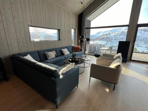 un soggiorno con divano blu e 2 sedie di The Panoramic Chalet a Stranda