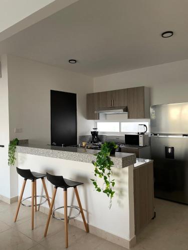 a kitchen with a counter and two stools in it at Departamento exclusivo Liverte in Cancún