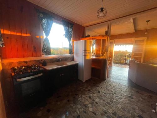 eine Küche mit einem Kühlschrank, einer Spüle und einem Fenster in der Unterkunft Chalé acima das nuvens - Serra da Bocaina in São José do Barreiro