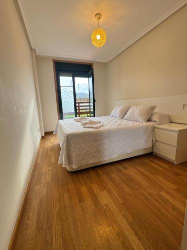 a bedroom with a large bed and a wooden floor at Apartamento Herosa 2 Spa in San Miguel de Reinante