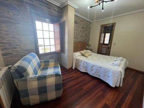 a bedroom with a bed and a chair in it at Hotel Casa Alberto in Castro Caldelas
