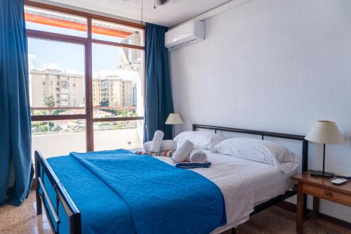 a bedroom with a bed with a blue blanket and a window at Nogalera apartamento 3 dormitorio con piscina in Torremolinos