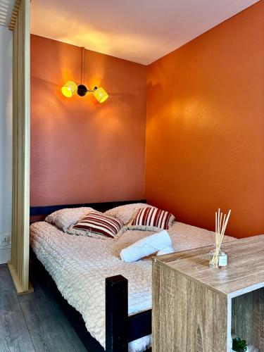 une chambre avec un lit avec un mur orange dans l'établissement LaTierraCota Centre ville Wifi Netflix, à Périgueux