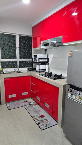 cocina con armarios rojos y nevera en Homestay T'Sya, Batu Buruk, en Kuala Terengganu