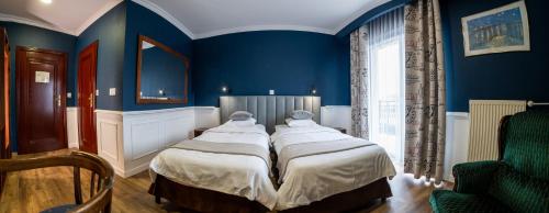 a bedroom with a large bed with blue walls at Grand Częstochowa in Częstochowa