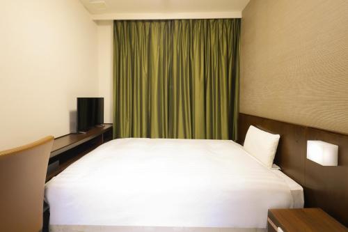 a bedroom with a white bed and a green curtain at Dormy Inn Matsumoto in Matsumoto
