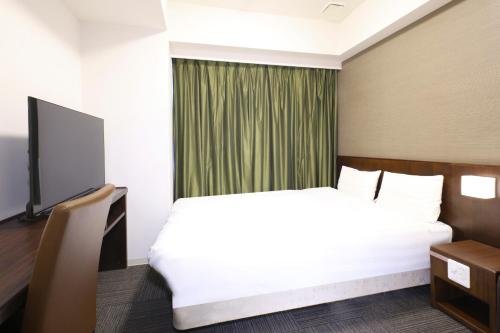 a hotel room with a bed and a television at Dormy Inn Matsumoto in Matsumoto