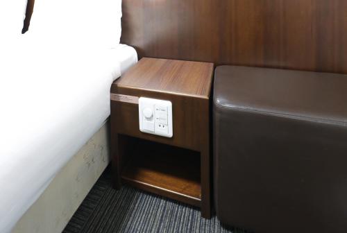 a small cabinet next to a bed in a room at Dormy Inn Matsumoto in Matsumoto
