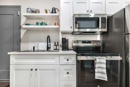 Una cocina con gabinetes blancos y un refrigerador de acero inoxidable. en Dynamic Stay Connected Comfort Steps from Atrium, en Macon