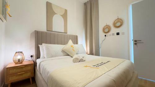 Palm Grove Elegant 2BR Oasis في أبوظبي: غرفة نوم بسرير ابيض كبير عليها شمعتين