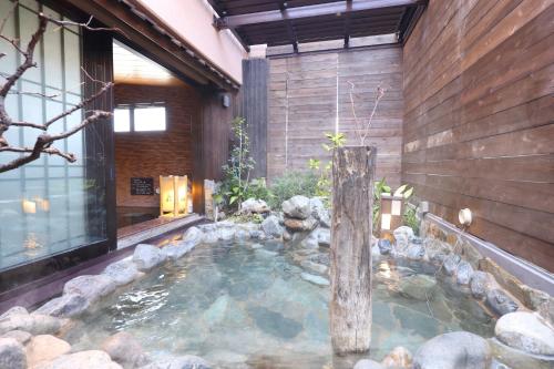 a large pool of water in a house with rocks at Dormy Inn Matsumoto in Matsumoto