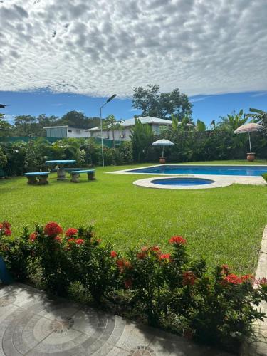 a park with benches and flowers in the grass at Hotel Sueños de María in Uvita