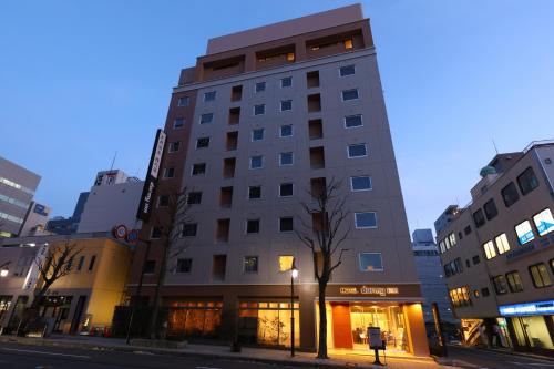 a tall building on a city street at night at Dormy Inn Matsumoto in Matsumoto