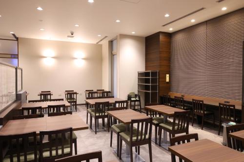 a dining room with wooden tables and chairs at Dormy Inn Matsumoto in Matsumoto