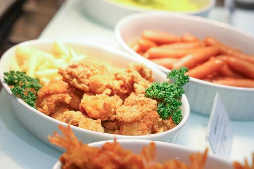 a bowl of food with broccoli and carrots on a table at Dormy Inn Matsumoto in Matsumoto
