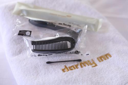 a black comb and a plastic bag on a white towel at Dormy Inn Matsumoto in Matsumoto