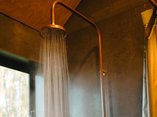 a shower with a hose hanging from the ceiling at Secluded Off-Grid Cabin in the Hunter Valley - Leo in Pokolbin