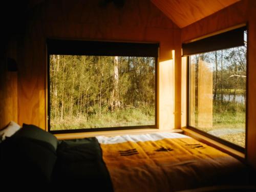a bedroom with a bed and a large window at Secluded Off-Grid Cabin in the Hunter Valley - Leo in Pokolbin
