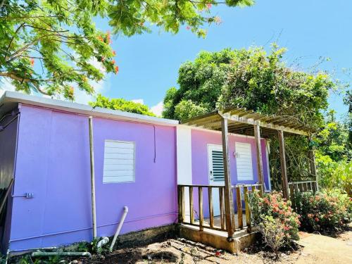 a pink house with a porch at Purple Sunset - Walk to Malecon & Beaches in Vieques