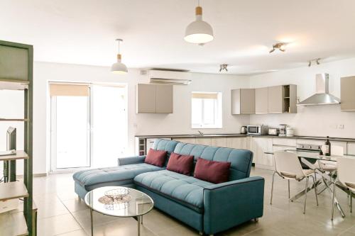 a living room with a blue couch and a kitchen at Luxury 3 Bedroom Apartment in Sliema - Walk to Beach & Dining in Sliema