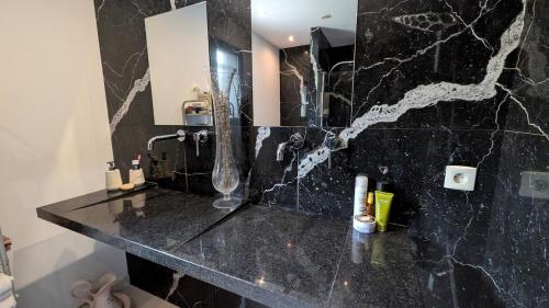 une salle de bain avec un comptoir en marbre noir et un miroir dans l'établissement Villa with sea and mountain views, à Furiani