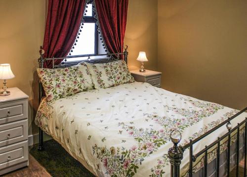 a bedroom with a bed and a window with red curtains at Beech Tree Park Cottages in Hatfield
