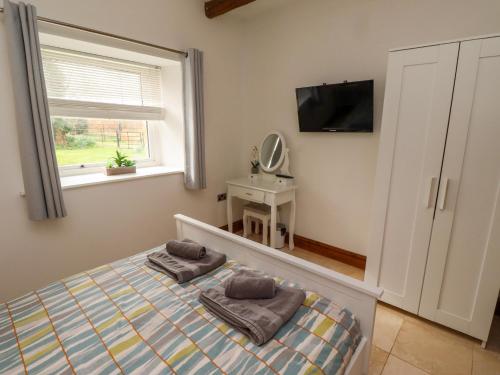 a bedroom with a bed and a tv and a window at Christon Well Cottage in Alnwick
