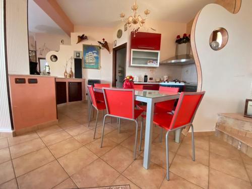 a kitchen with red chairs and a table at Villa Sunset in Campofelice di Roccella