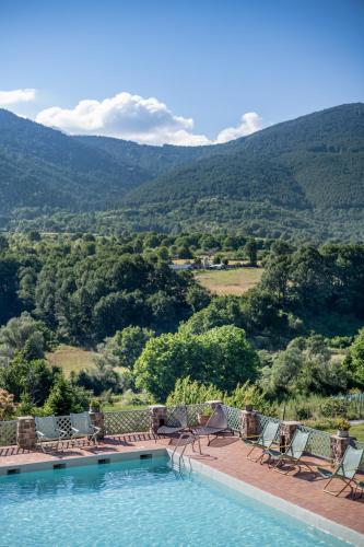 a swimming pool with chairs and mountains in the background at Ktima Bellou in Ágios Dimítrios
