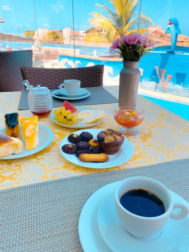 a table with plates of food and a cup of coffee at Planet Dunas Residence in Aquiraz
