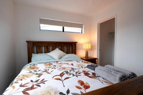 ein Schlafzimmer mit einem Bett mit geblümter Tagesdecke in der Unterkunft Brand New 2BR Home in City in Christchurch