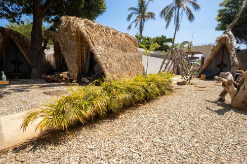 a small house with a straw roof and palm trees at Hidden Port TTipis Vista Carrizalillo in Puerto Escondido