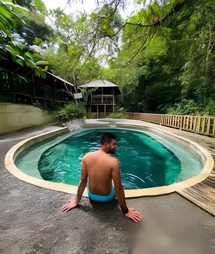 a man sitting in front of a swimming pool at Eco cabaña Frente al Mar & Paraíso en "Nuquí " in Termales - agua caliente - nuqui