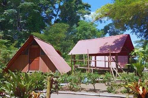 a house with a red roof next to a garden at Eco cabaña Frente al Mar & Paraíso en "Nuquí " in Termales - agua caliente - nuqui
