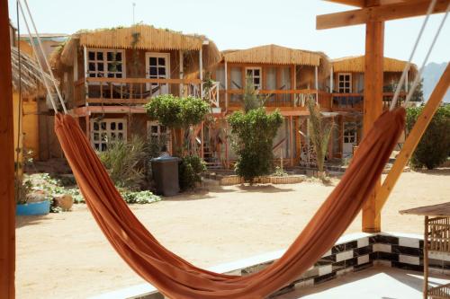a hammock in front of a group of houses at Green Beach Camp & Hotel in Nuweiba