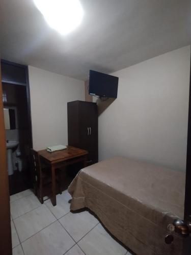 a bedroom with a bed and a desk and a television at Gaba Hotel in Mollendo