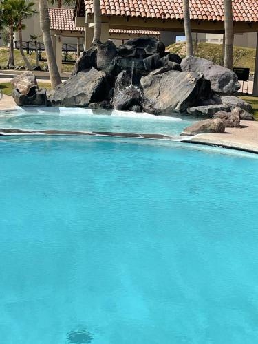 a swimming pool with blue water and a rock formation at Ocean View Condo with Pools and Easy Beach Access in Las Conchas